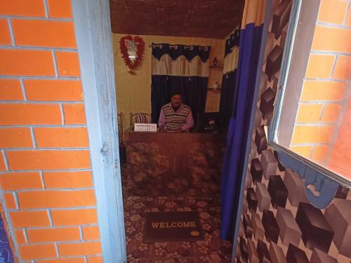 Un uomo seduto ad una scrivania in un corridoio di OYO A.R. Lodge a Durgāpur