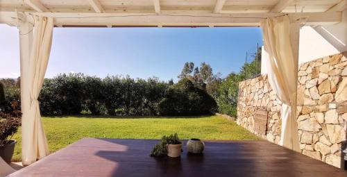 eine Terrasse mit einem Tisch und einer Steinmauer in der Unterkunft Green House in Siniscola