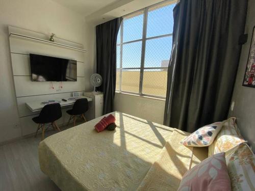 um quarto com uma cama, uma secretária e uma janela em Loft aconchegante próximo a Feirinha do Alto em Teresópolis