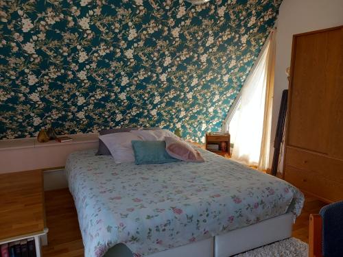 una camera da letto con un letto e carta da parati floreale di La Chambre d'Agapè a Fouesnant