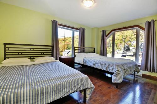 een slaapkamer met 2 bedden en een groot raam bij Chalets Alpins-43 Chemin des Skieurs in Stoneham