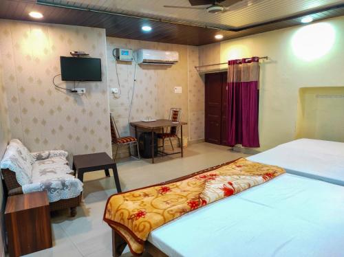 1 dormitorio con 1 cama, escritorio y TV en LD Guest House, en Ayodhya