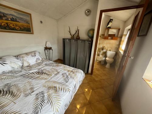 a bedroom with a bed and a bathroom at La maison des Passereaux in Callian