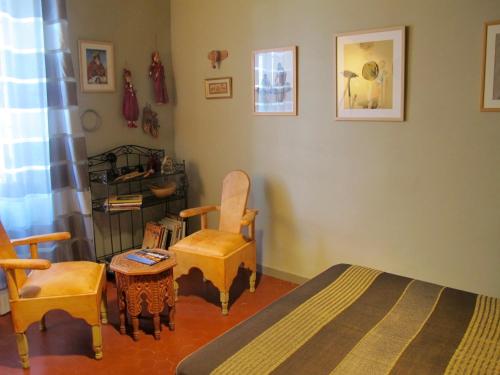a bedroom with a bed and two chairs and a table at tombe la nèfle in Avignon