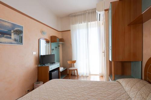 a bedroom with a bed and a desk with a television at Hotel Britannia Rimini Marina centro in Rimini