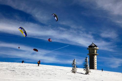 um grupo de pessoas soltando pipas na neve com um farol em Sope Skylodge 01 - Eldison's Bobbele - Oberried, Schauinsland em Oberried