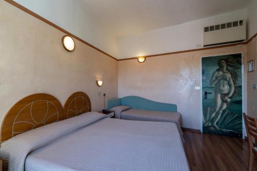 a bedroom with two beds and a painting on the wall at Hotel Britannia Rimini Marina centro in Rimini