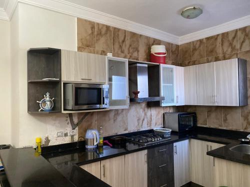 a kitchen with wooden cabinets and a microwave at Marseilia blue bay asia in Ain Sokhna