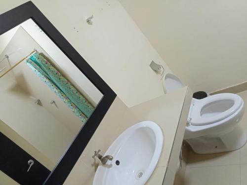 La salle de bains est pourvue d'un lavabo, de toilettes et d'un miroir. dans l'établissement HOTEL AVICTORIA, à Tonsupa