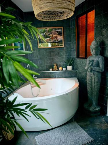 La salle de bains est pourvue d'une baignoire et d'une statue. dans l'établissement La jungle insolite, SPA, Écran cinéma, Lit à baldaquin king size, day use, 10 min centre, à Amiens
