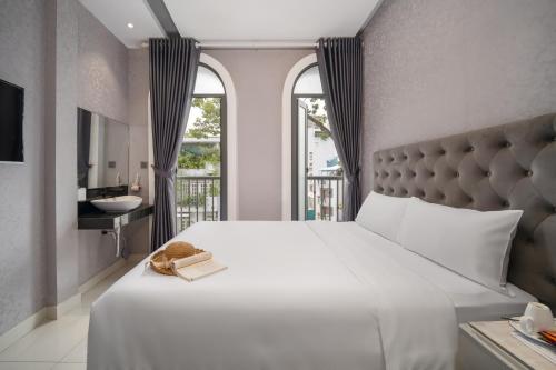a bedroom with a large white bed and a bathroom at Mari Hotel By Connek in Ho Chi Minh City
