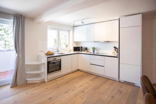 a kitchen with white cabinets and a wooden floor at Sope Skylodge 03 - Elvin's Hüsle - Oberried, Schauinsland in Oberried