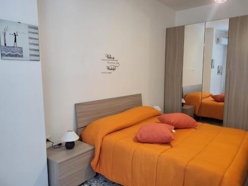 una camera da letto con un letto con lenzuola arancioni e uno specchio di Garibaldi Square Central City a Bari