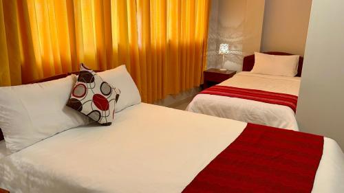 um quarto com 2 camas e uma cortina laranja em Hostal Restaurant Gocta em Cocachimba