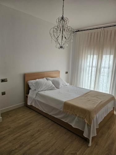 a bedroom with a large bed and a chandelier at Ca Vicent in Estivella