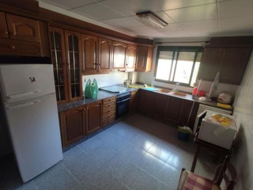 - une cuisine avec des placards en bois et un réfrigérateur blanc dans l'établissement Apartamento Universidad, à Ontinyent