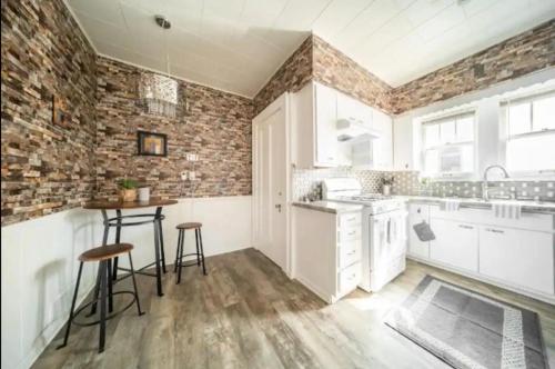 una cocina con armarios blancos y una pared de ladrillo en 4 Bdrm in Highland Square, Akron, en Akron