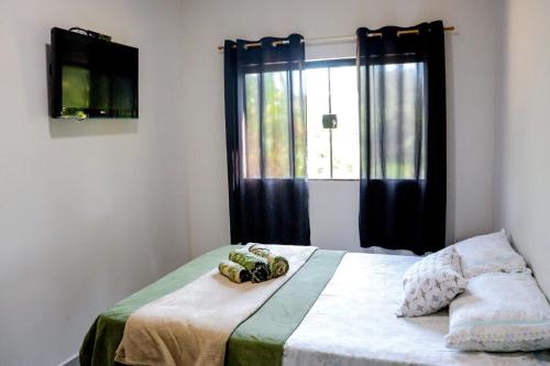 a bedroom with a bed with a window and a television at Pousada - Pesqueiro do Brasinha 