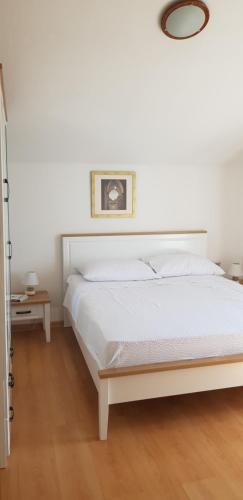 Un dormitorio con una cama blanca con una foto en la pared en Apartments Zafranović, en Prvić Luka