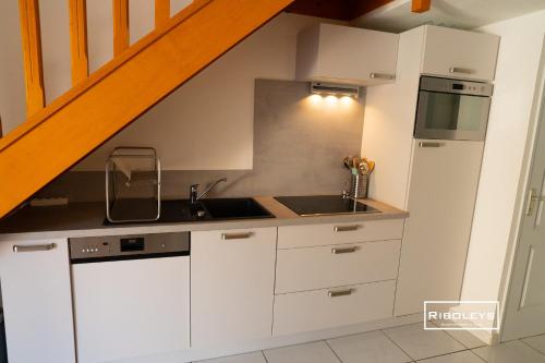 eine Küche mit weißen Schränken und einem Waschbecken in der Unterkunft Vias-Plage - Villa climatisée à 600m de la plage in Vias