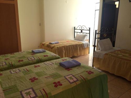 a room with three beds and a chair at Hotel Misky Samay in Ayacucho
