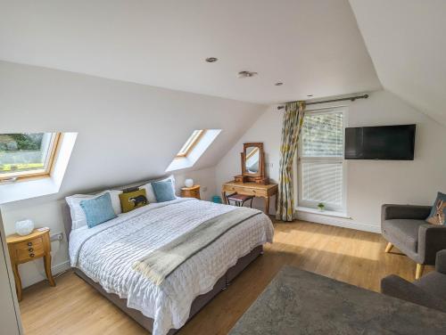 a bedroom with a bed and a chair and windows at Badgers Den in Linlithgow