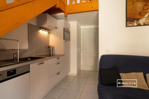 een keuken met een wastafel en een bank in een kamer bij Vias-Plage - Villa climatisée à 600m de la plage in Vias