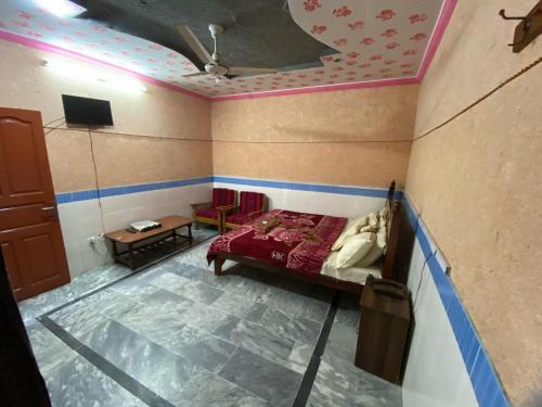 a bedroom with a bed and a table and a tv at Zain Hotel Abbottabad in Abbottabad