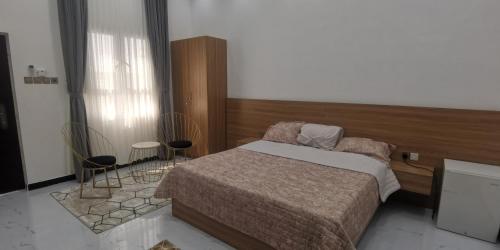 1 dormitorio con 1 cama y 2 sillas en نزوي, en Nizwa