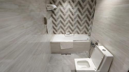 een badkamer met een wit toilet en een wastafel bij Almansour Hotel in Bagdad