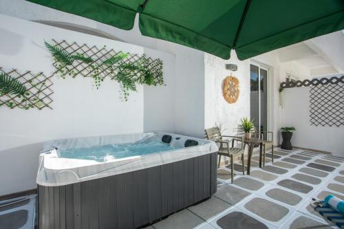 a hot tub in a patio with a green umbrella at CASA MIKELE by Sarikas Anthony Quinn Beach Faliraki - Ladikos Garden in Faliraki