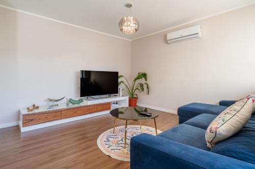 a living room with a blue couch and a tv at Gaia Terrace Apartamento Qian 2BR AC l Free Parking in Vila Nova de Gaia