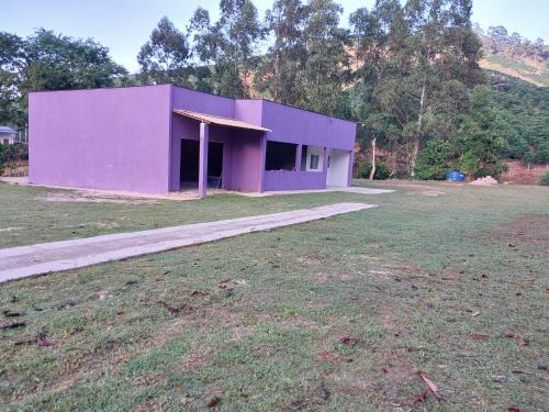 a purple building in a field next to a field at Chácara Aconchego na Serra in Caparaó Velho
