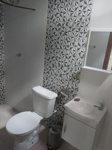 a white bathroom with a toilet and a sink at Chácara Aconchego na Serra in Caparaó Velho