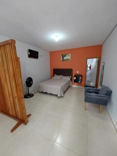 a bedroom with a bed and a couch and a chair at Chácara Aconchego na Serra in Caparaó Velho