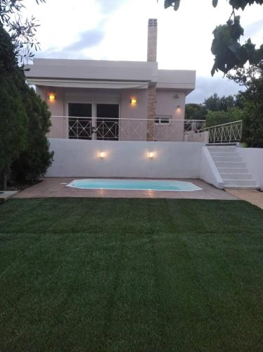 a house with a swimming pool in front of a yard at Cozy villa Vita Lagonisi in Kalívia Thorikoú