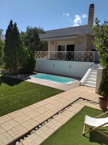 une maison avec une piscine dans une cour dans l'établissement Cozy villa Vita Lagonisi, à Kalívia Thorikoú