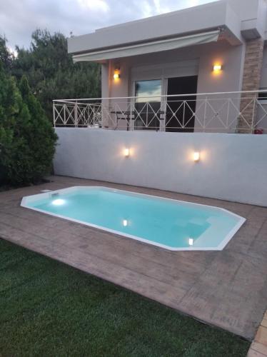 a swimming pool in front of a house at Cozy villa Vita Lagonisi in Kalívia Thorikoú