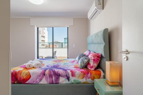 a bedroom with a colorful bed with a window at Gaia Terrace Apartamento Qian 2BR AC l Free Parking in Vila Nova de Gaia