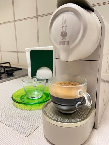a cup of coffee sitting on a stand next to a coffee maker at Casa Ganza in Pisa