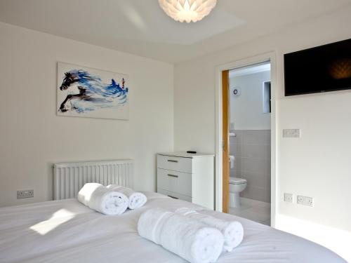 a white bedroom with a bed with towels on it at Black Sea Horse in Westward Ho