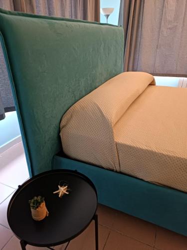 un divano verde con tavolo accanto a un letto di Casa Leopardi a Napoli a Napoli
