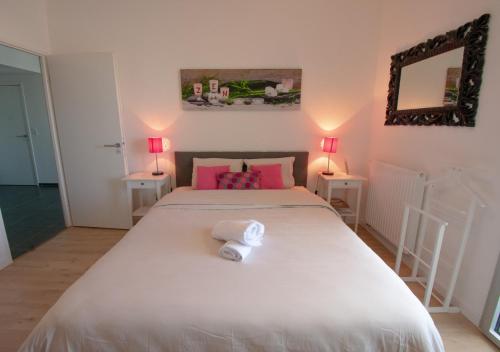 une chambre avec un grand lit blanc avec des oreillers roses dans l'établissement Appartement 90m2-Roof Top privé 100m2-Parking privé-Clim mobile, à Nantes