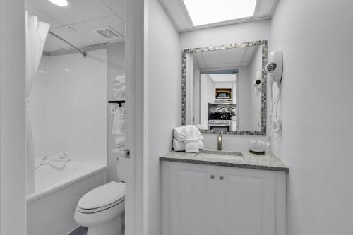 een witte badkamer met een toilet en een wastafel bij Boardwalk Resort: Ocean Breeze Retreat in Myrtle Beach