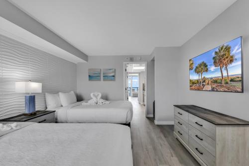 een witte slaapkamer met 2 bedden en een bureau bij Boardwalk Resort: Ocean Breeze Retreat in Myrtle Beach
