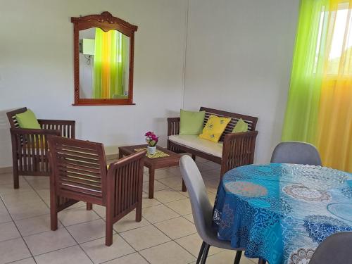 uma sala de estar com uma mesa e cadeiras e um sofá em Soleil bleu em Les Abymes