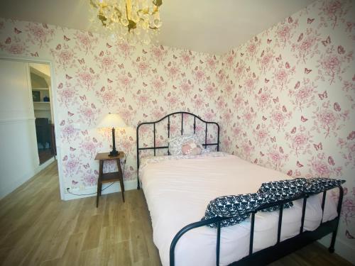 ein Schlafzimmer mit einem Bett mit rosafarbener Blumentapete in der Unterkunft Le cottage des artistes in Champigny-sur-Marne