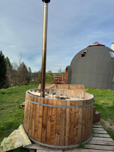 a large wooden barrel with a yurt in the background at Cichy Zakątek u Basi 