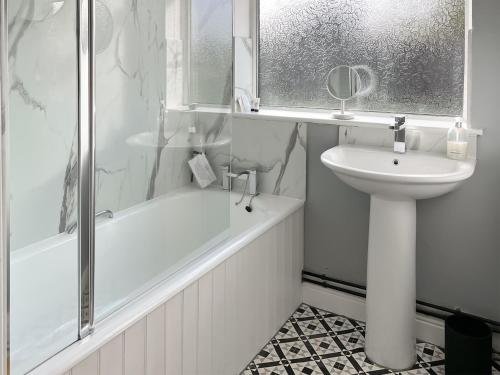 y baño blanco con lavabo, bañera y lavamanos. en Acres View en Hoveringham