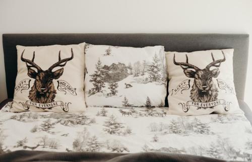 a bed with two pillows with deer heads on it at Krańcówka Szczyrk Górna in Szczyrk